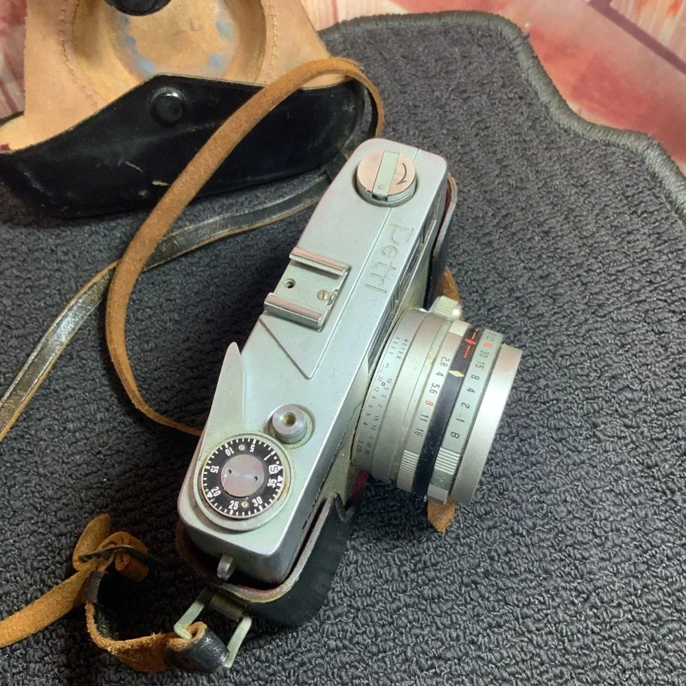 Vintage Petri camera with leather strap and cover.
