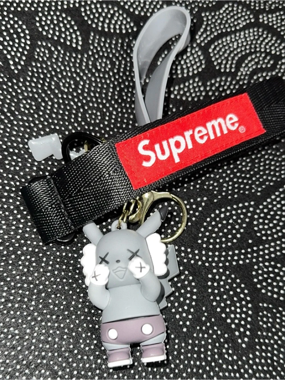 Supreme black and red lanyard with gray KAWS-style keychain